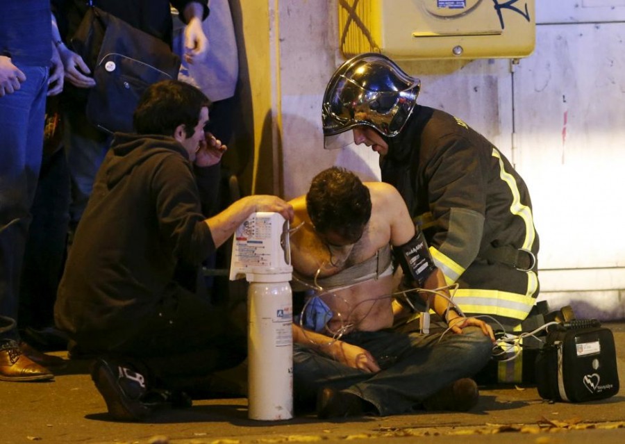 French fire brigade members aid an injured individual near the Bataclan concert hall following fatal shootings in Paris, France, November 13, 2015. REUTERS/Christian Hartmann