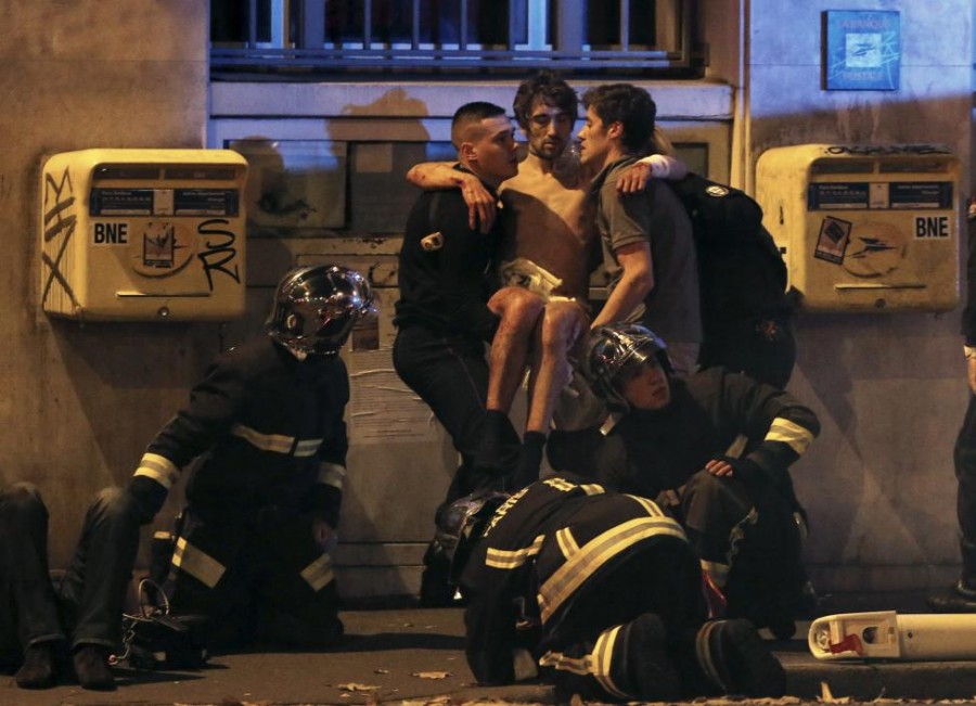French fire brigade members aid an injured individual near the Bataclan concert hall following fatal shootings in Paris, France, November 13, 2015. At least 30 people were killed in attacks in Paris and a hostage situation was under way at a concert hall in the French capital, French media reported on Friday. REUTERS/Christian Hartmann